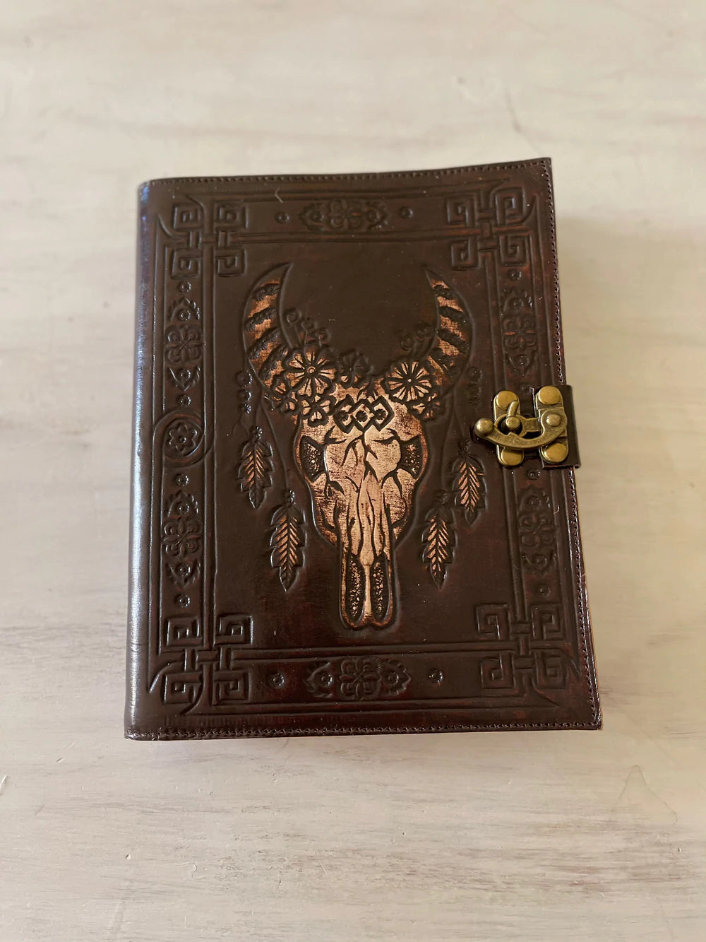 Dark leather journal with hand-tooled bull skull design on woven mat - Gypsy Toro boho journal from Bohemian Love Runway