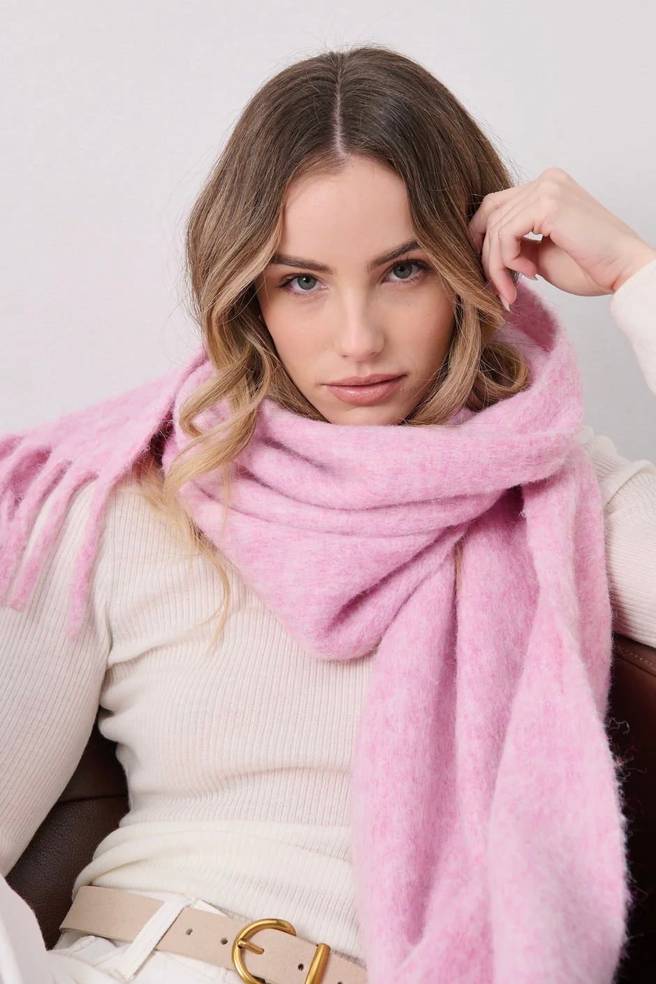 Woman in a soft pink fluffy boho scarf and cream top gazing at camera - Australian winter scarf style.