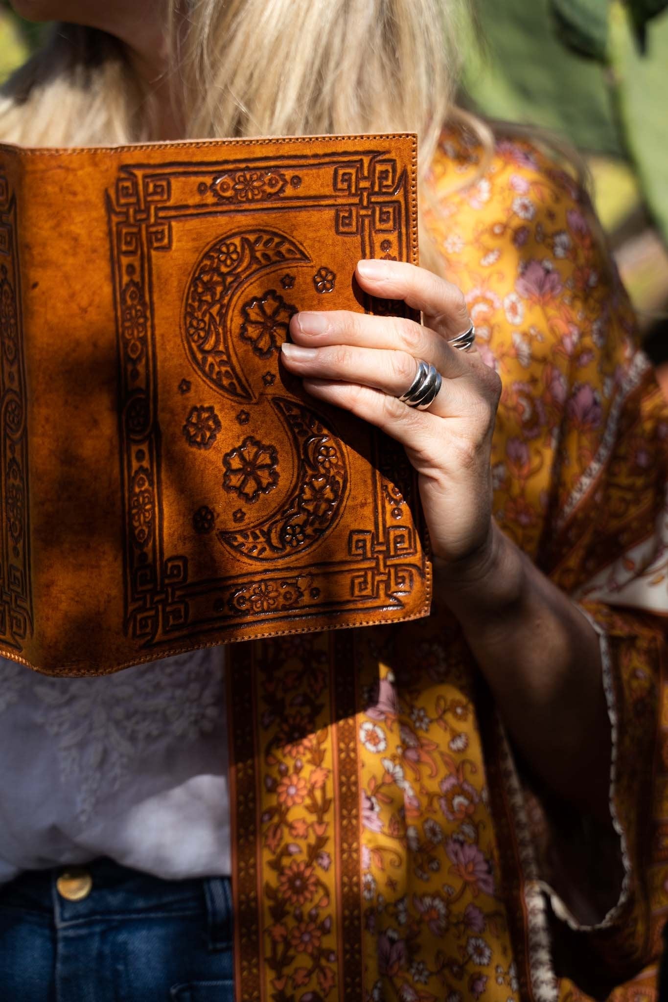 Woman in a golden paisley kimono holding an embossed boho journal in sunlight - Secret Whispers Journals Australia