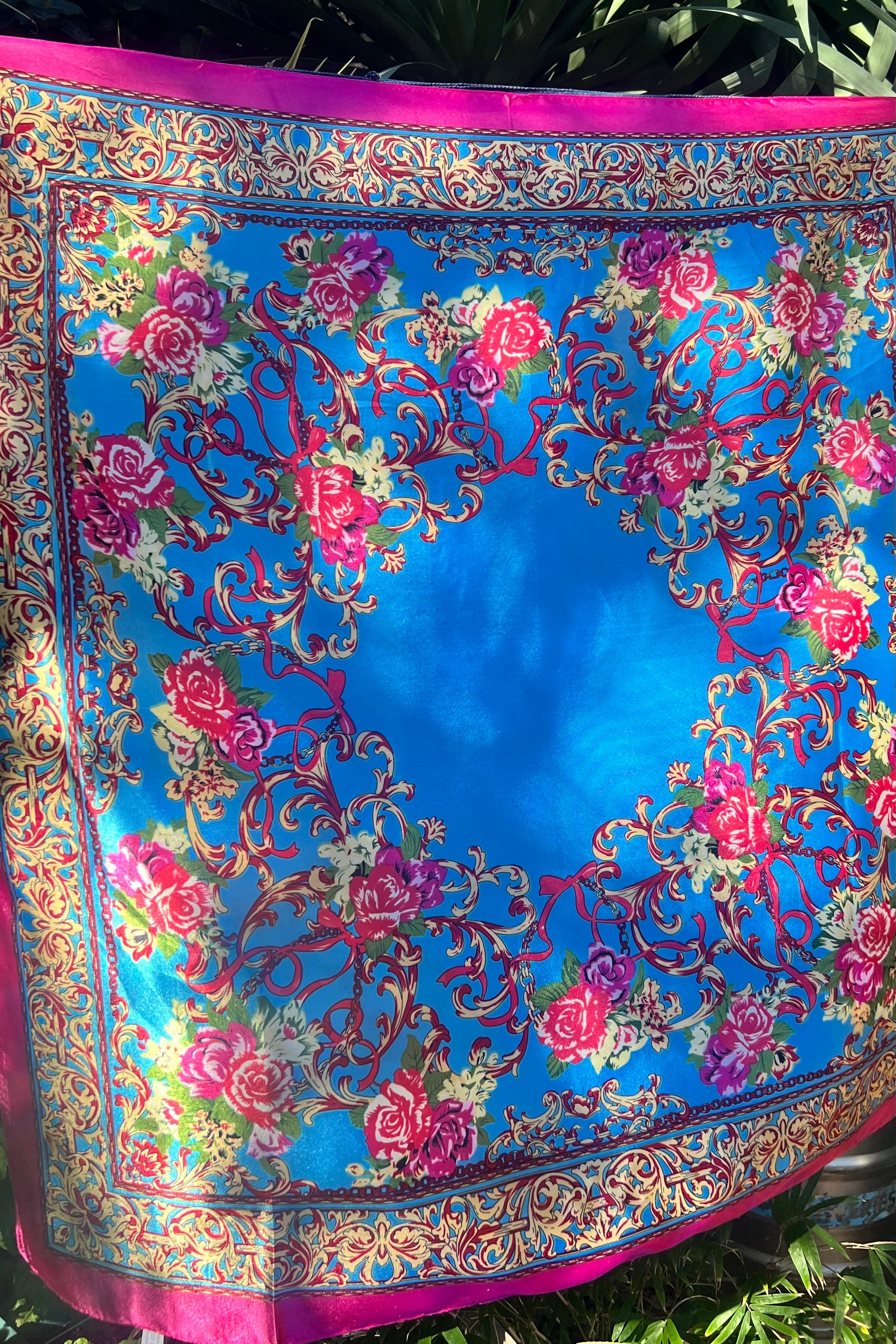 Floral satin scarf in vivid cobalt blue with an ornate pink rose and god baroque border, displayed flat with a hot pink edge and symmetrical floral frame.