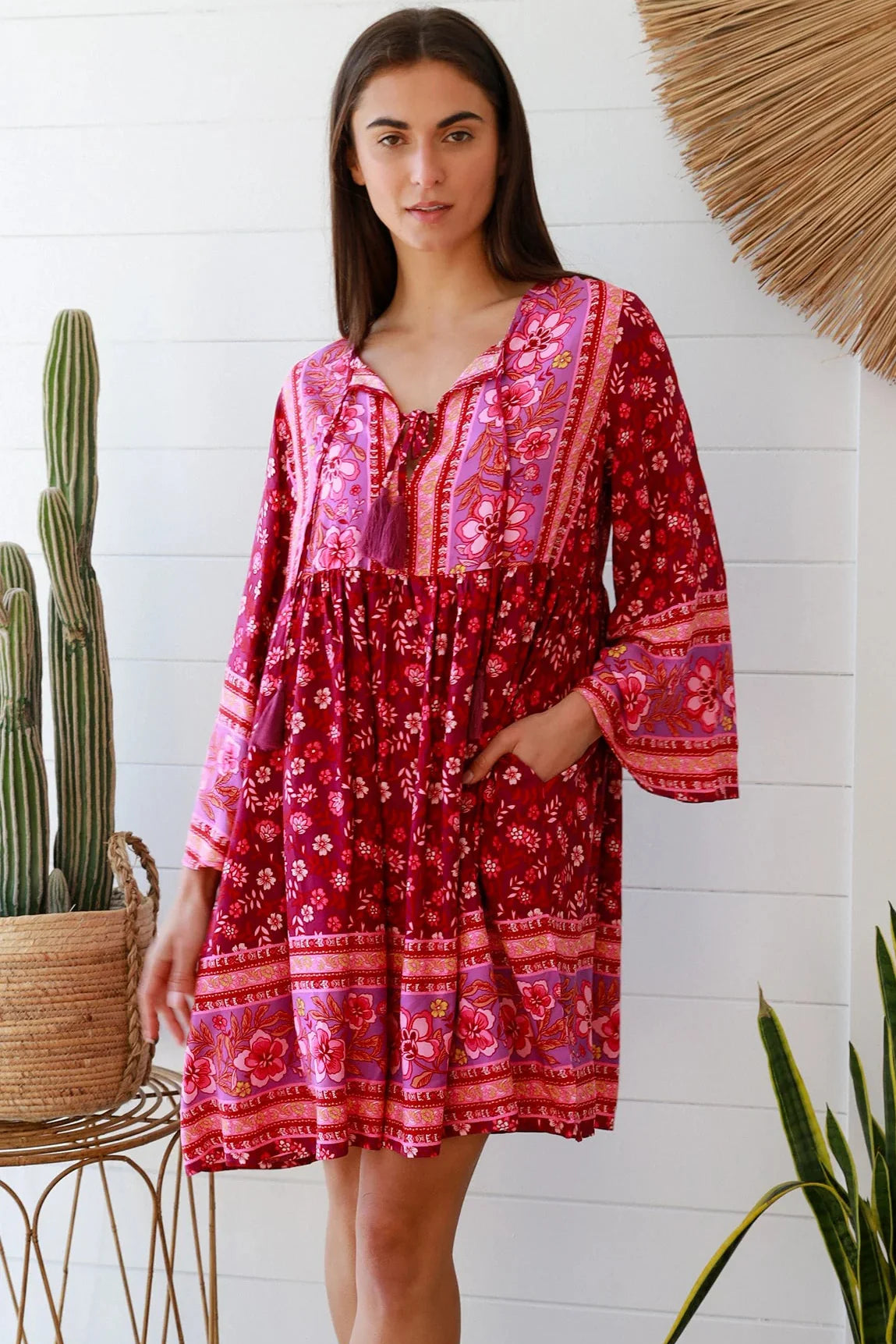 Woman wearing a raspberry floral bohemian mini dress with border print and flared sleeves Australian boho fashion