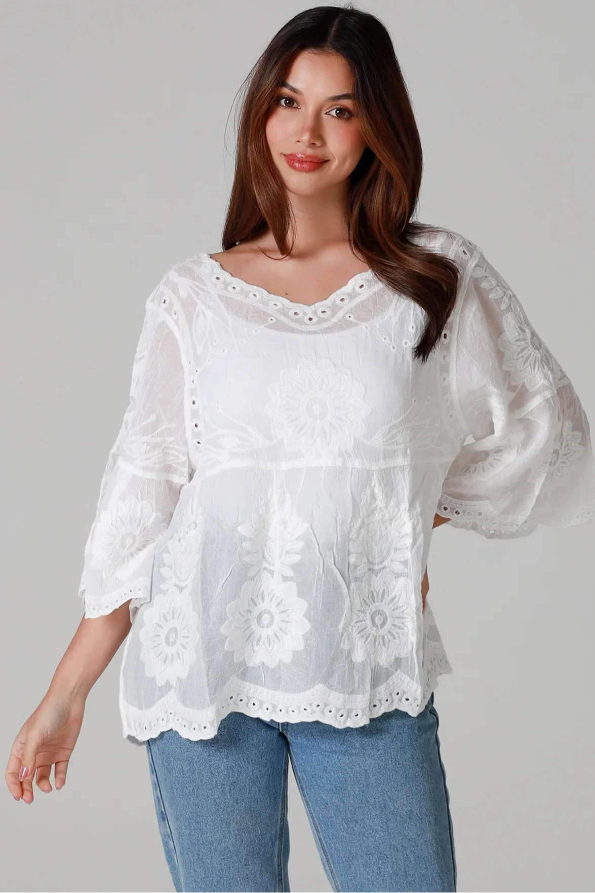 Model wearing a white embroidered boho blouse with scalloped hem and sleeves, styled with denim — perfect for relaxed Australian style.