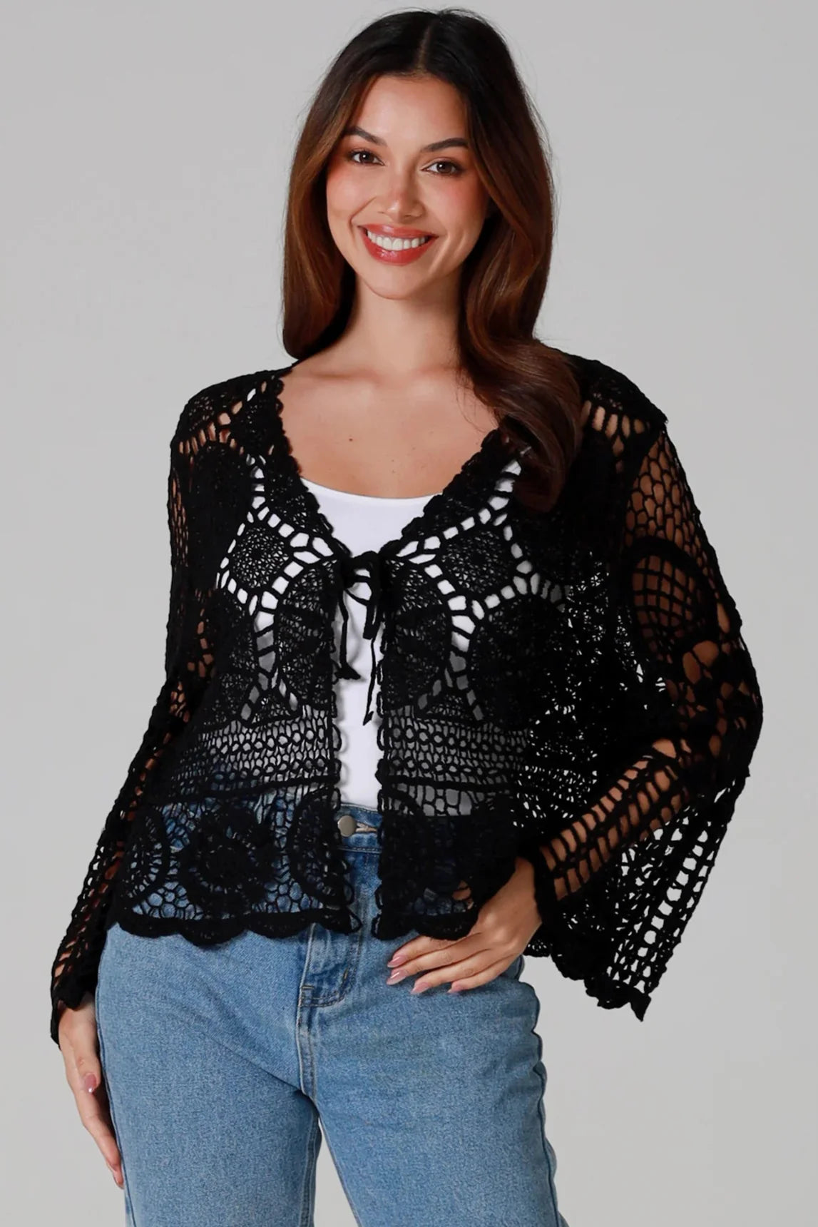 Woman wearing a black crochet cardigan with flared sleeves and floral motifs, paired with light denim jeans - Boho Chic Crochet Australia.