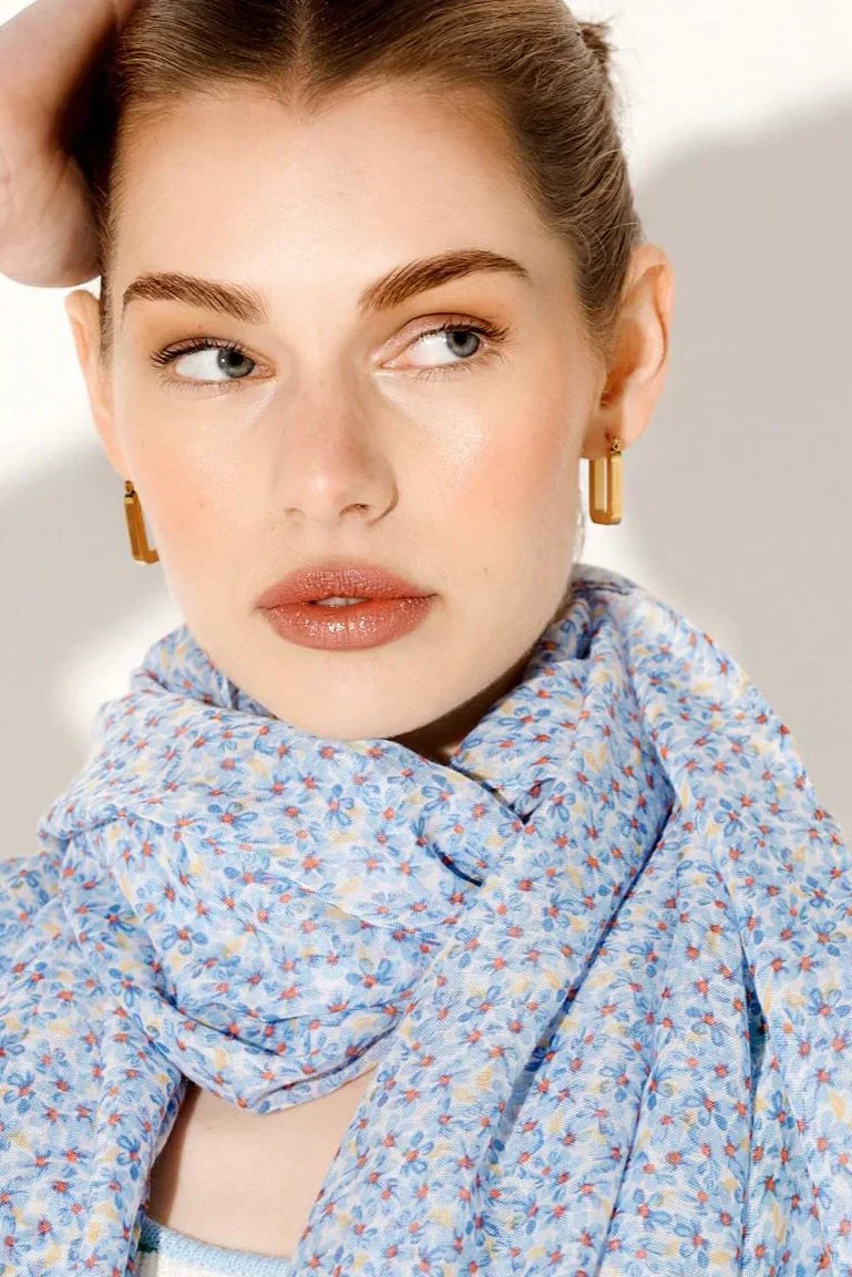 Model wearing soft blue boho scarf with floral print, styled in a wrap around the neck - luxe bohemian fashion with vintage elegance and wanderlust appeal.