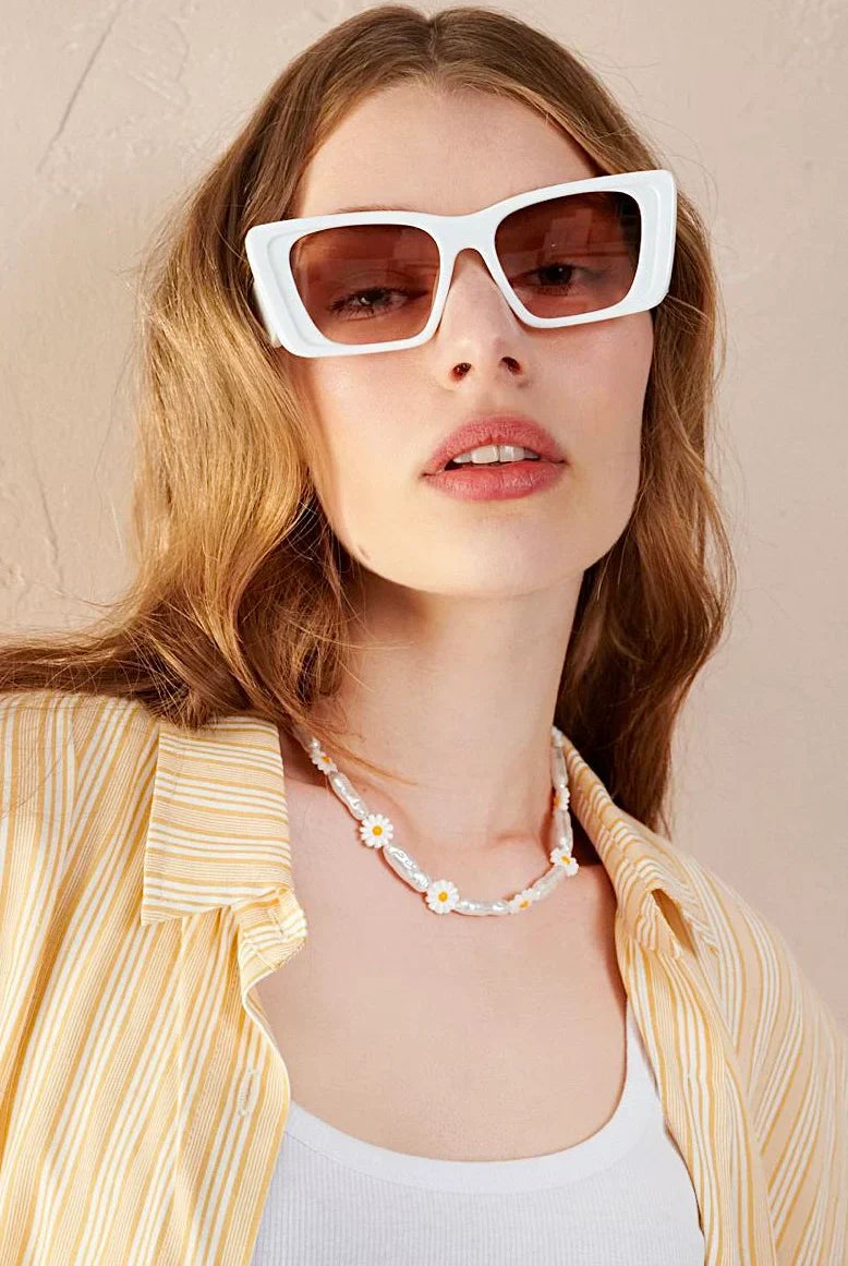 Model wearing oversized white sunglasses, shell necklace, and striped shirt - boho accessories from Bohemian Love Runway.