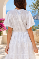 Angelique white embroidered cotton mini dress by Salty Palm with lace V-neck, tassel ties, flutter sleeves and tiered skirt