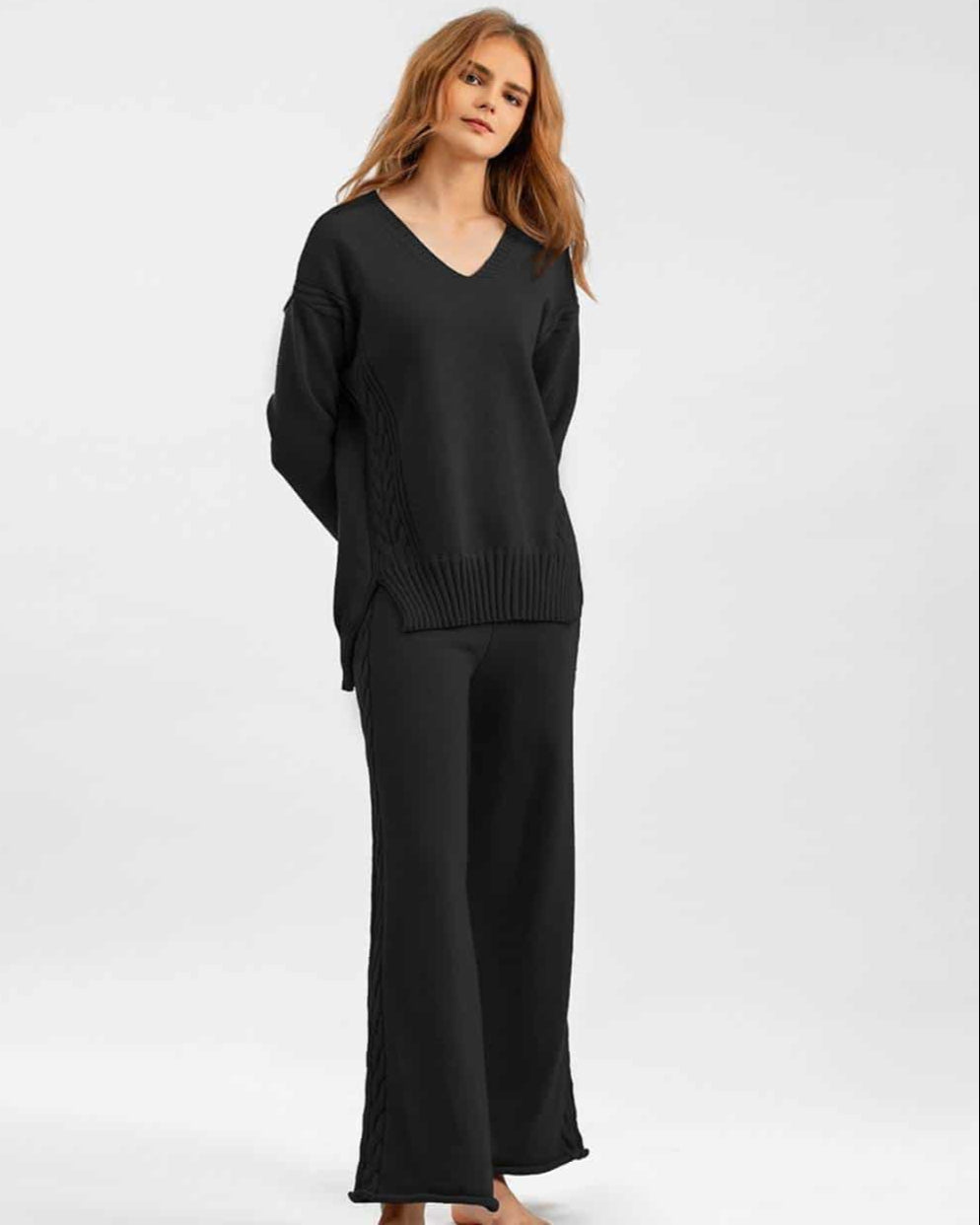 Woman wearing black cable knit lounge set with wide-leg pants and relaxed V-neck sweater —100% cotton winter knitwear.