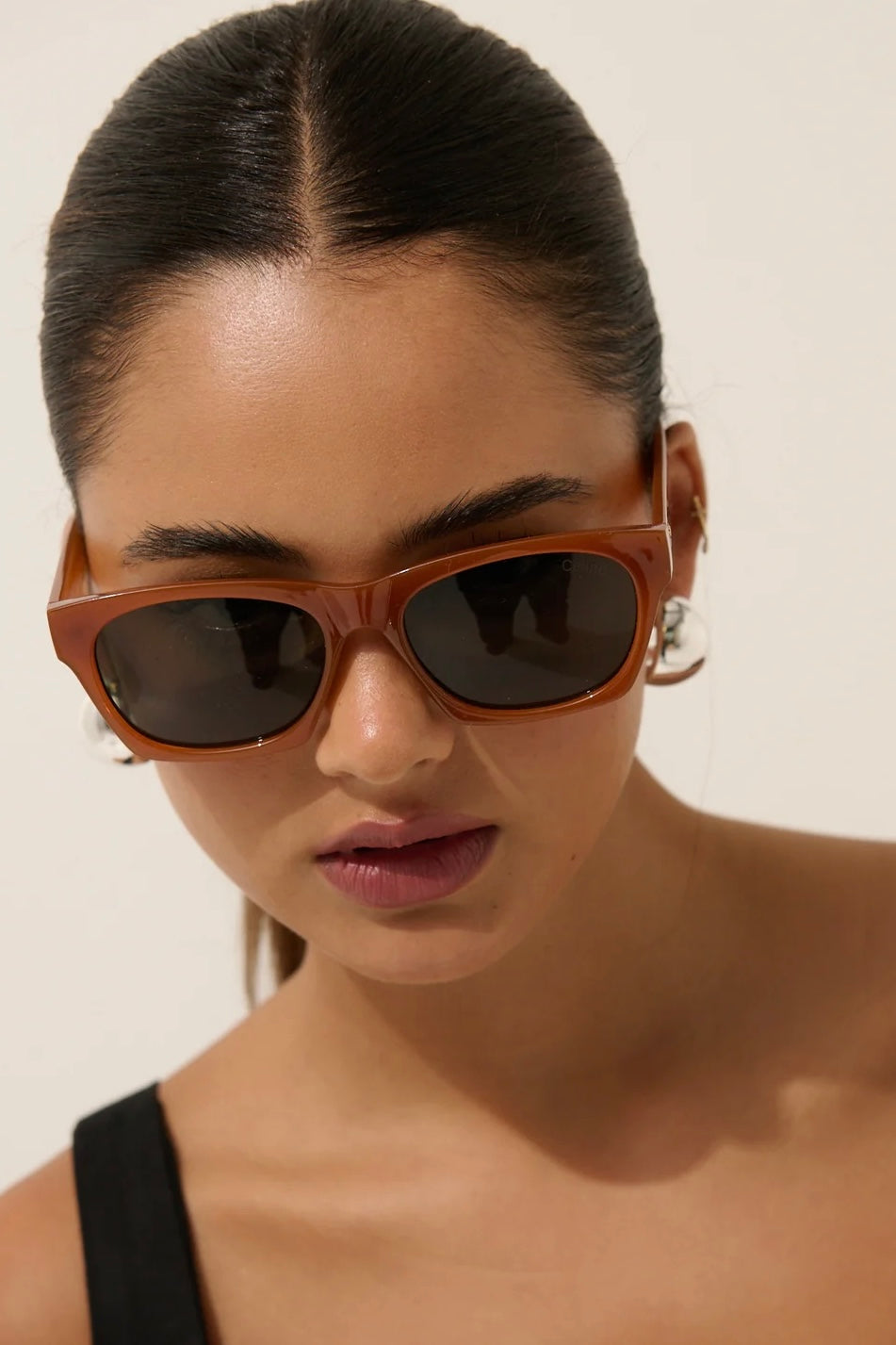 Woman in brown square boho sunglasses with slick hair and dark lip— vintage-inspired summer style Australia.