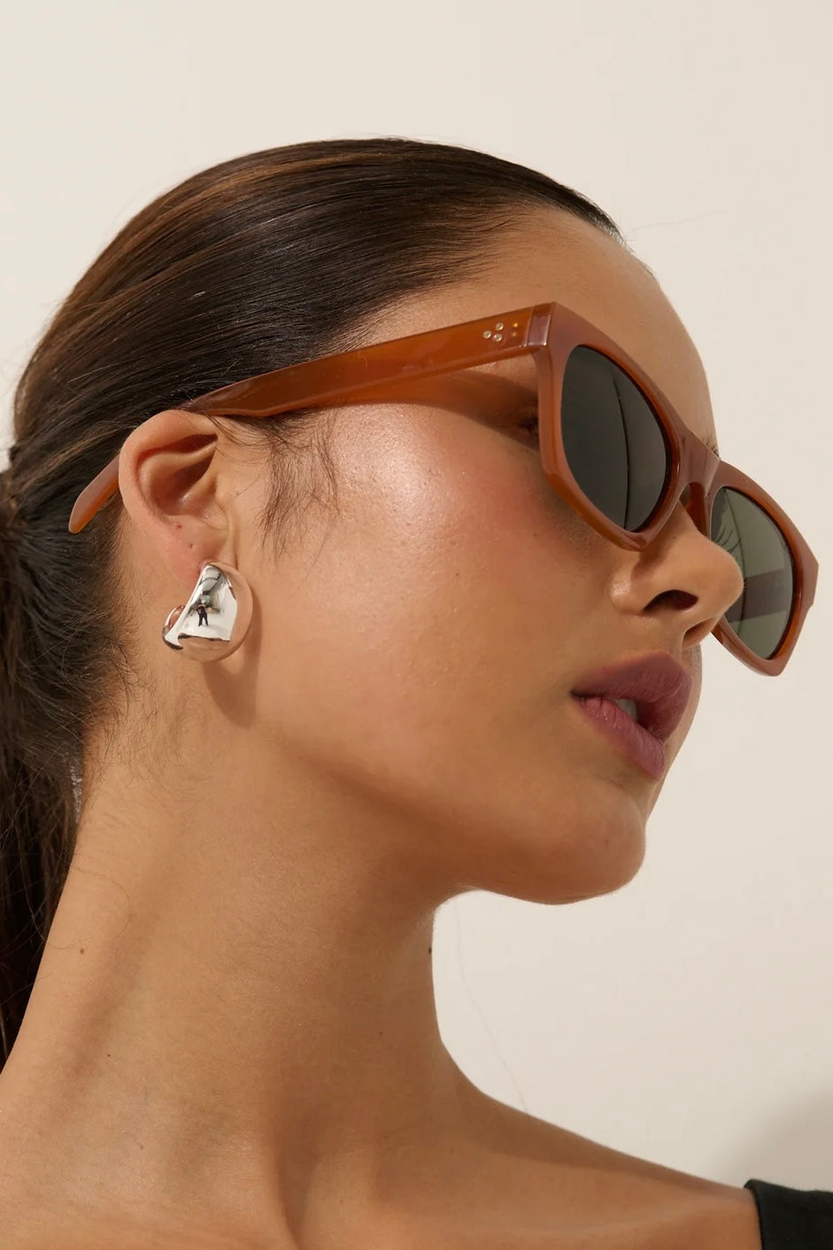 Woman in brown square boho sunglasses with slick hair and dark lip— vintage-inspired summer style Australia.