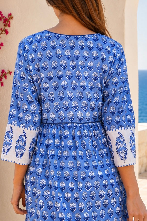 A woman wearing a blue and white printed cotton kurta, shown from the back. The dress features a delicate blue floral block print on a white base, with white cuffs decorated with block print border.