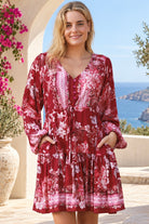 Claudette ruby red floral boho mini dress with blouson sleeves, drawstring waist, pockets and border print frill hem