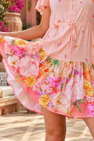 Abigail peach floral rayon boho mini dress with flutter sleeves, drawstring waist, pockets and oversized rose print hem | Bohemian Love Runway