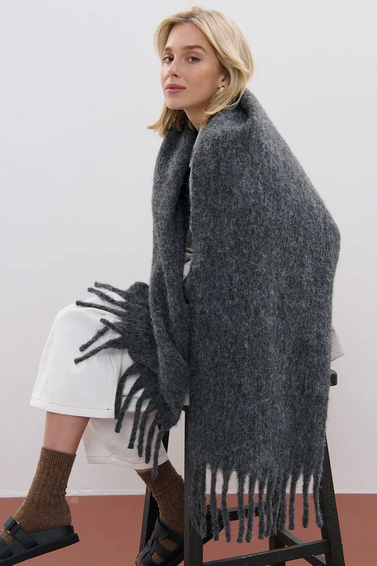 Woman wrapped in a charcoal fluffy boho wool blend scarf with fringe - The Midnight Hour winter wrap from Bohemian Love Runway.