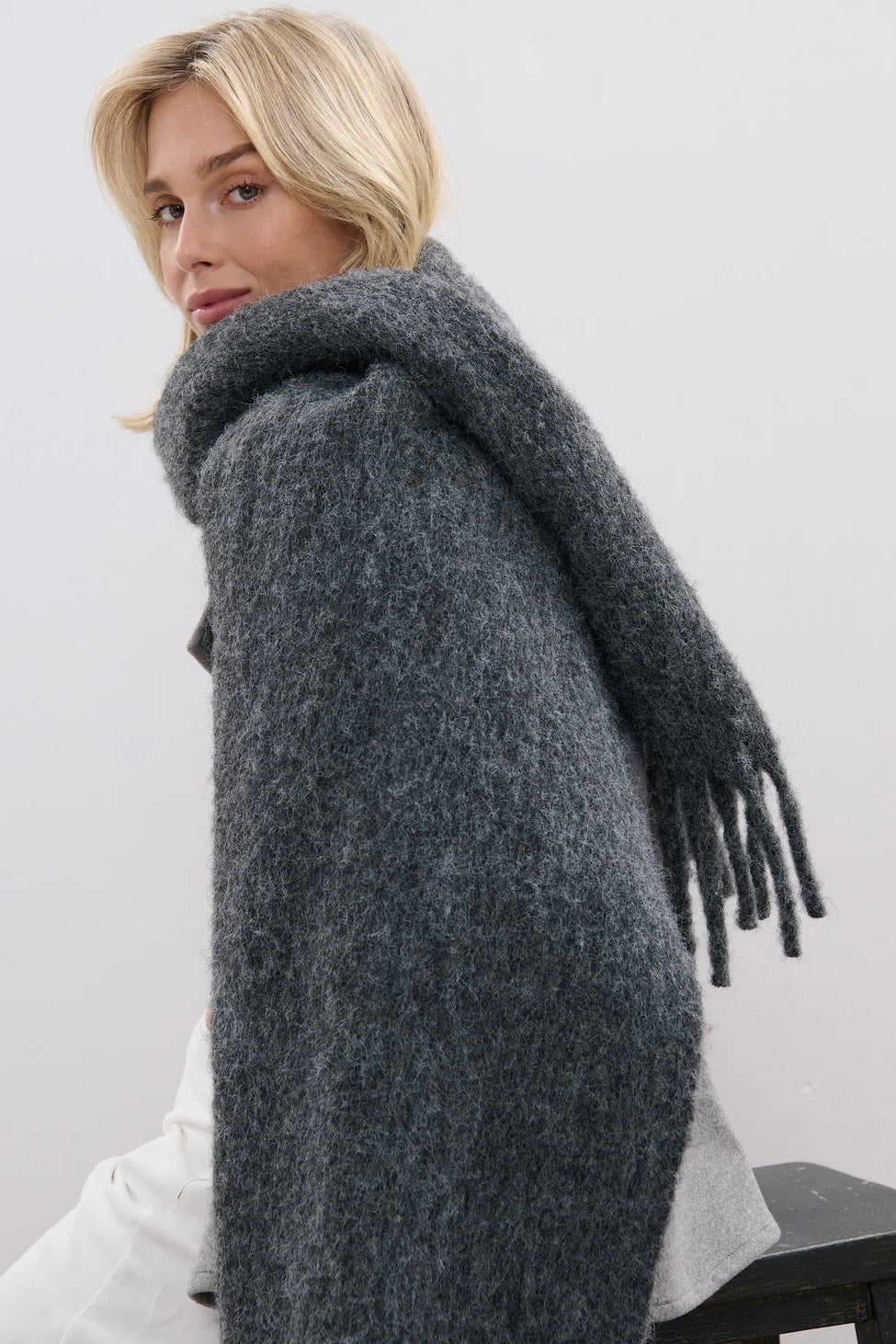 Woman wrapped in a charcoal fluffy boho wool blend scarf with fringe - The Midnight Hour winter wrap from Bohemian Love Runway.