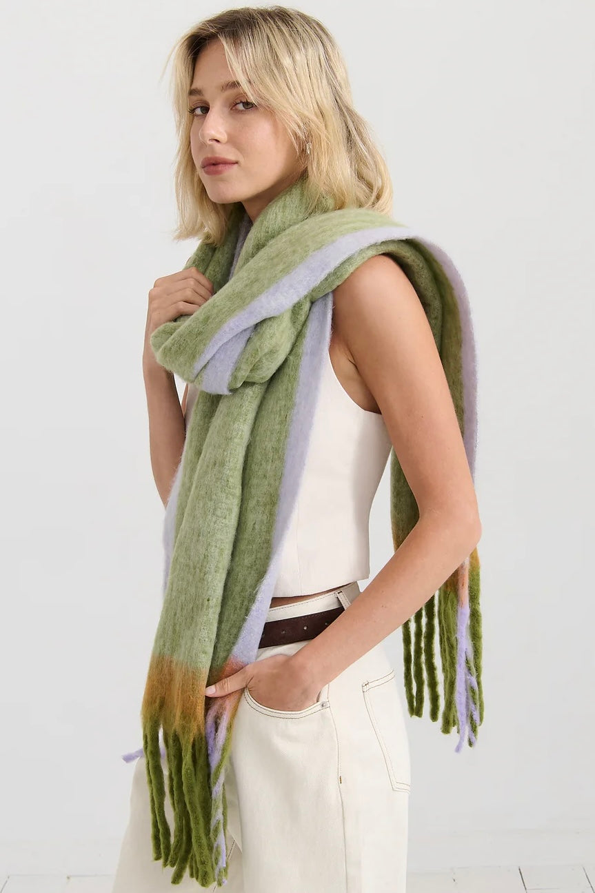 Woman in oversized green and lilac checkered scarf with fringe, wrapped in soft winter layers - Bohemian Love Runway scarf.