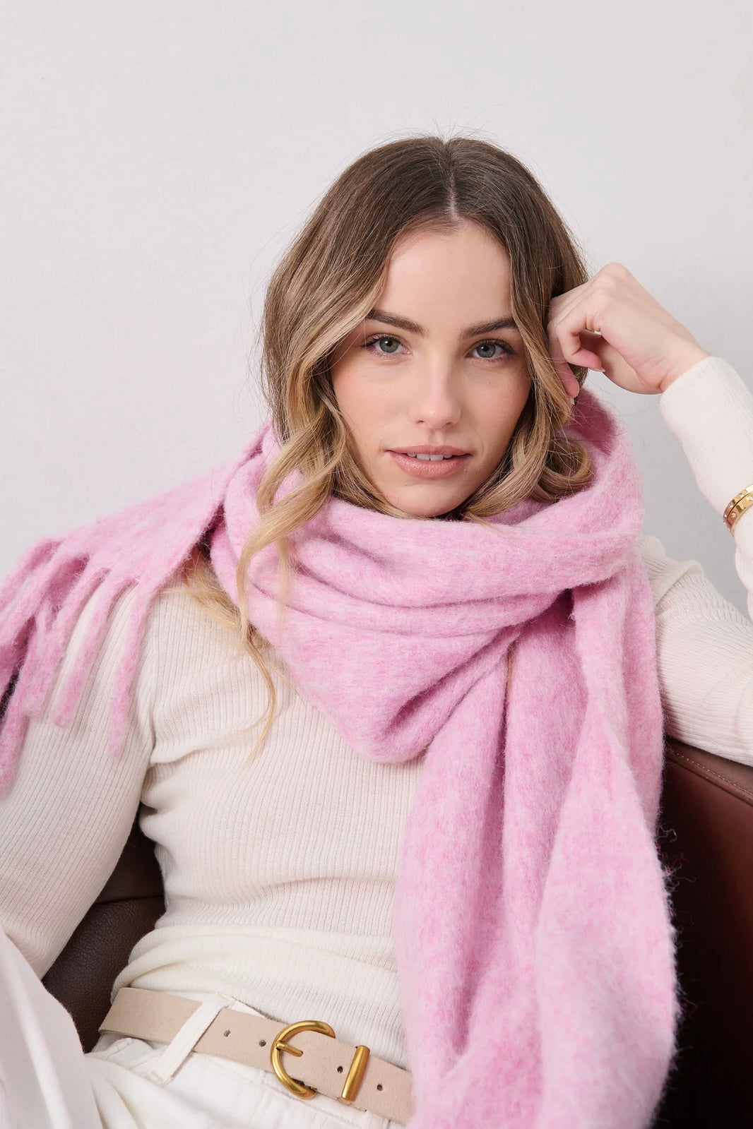 Woman in a soft blush pink boho scarf with tassels styled over a knit jumper - Rosabella scarf Australia.