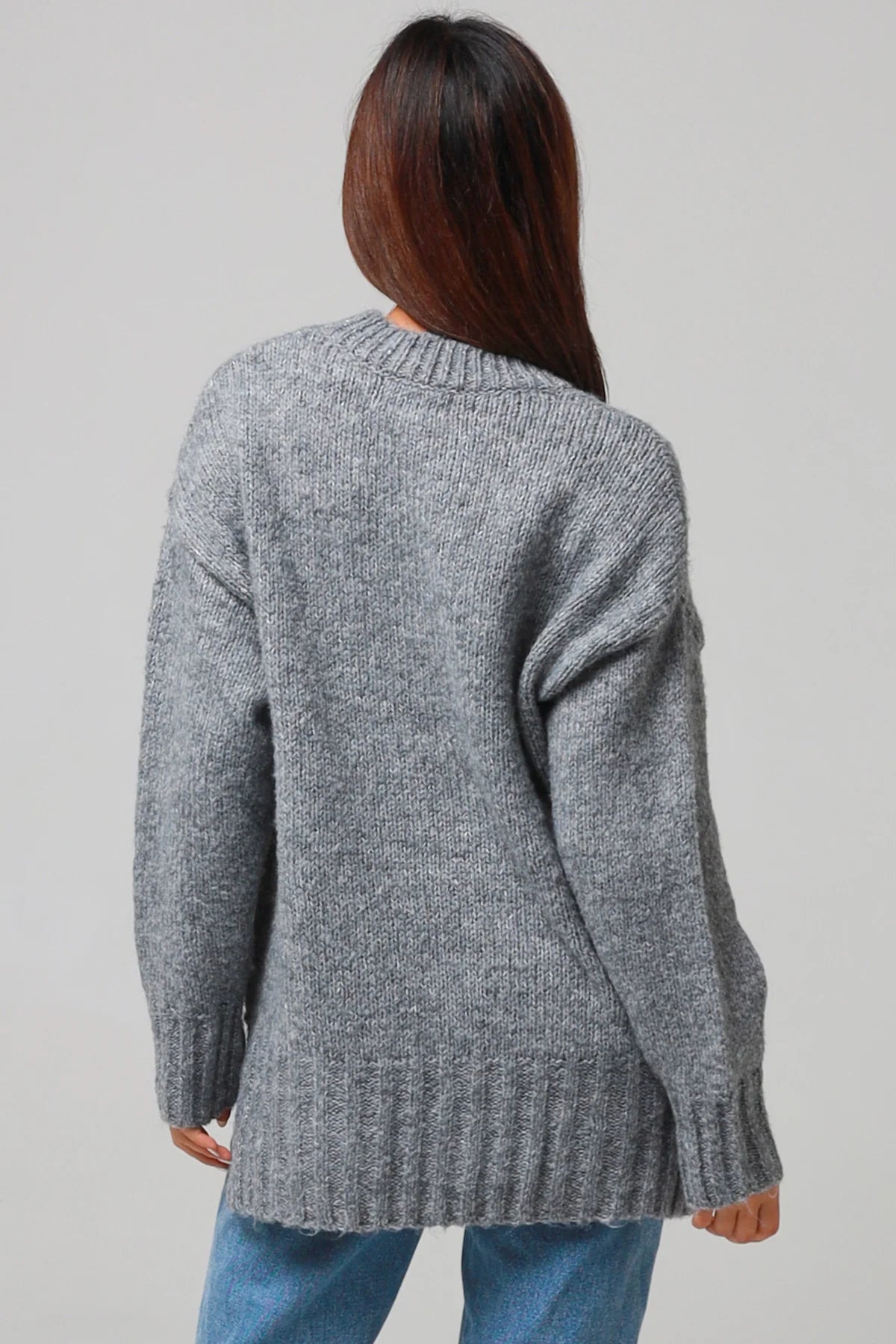 Woman wearing a grey wool blend knit jumper with ribbed cuffs and hem- boho winter jumper Australia.