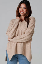 Woman wearing a biscotti colour wool blend cable knit jumper with relaxed fit and v-neckline - Caldra Knit Jumper Australia.