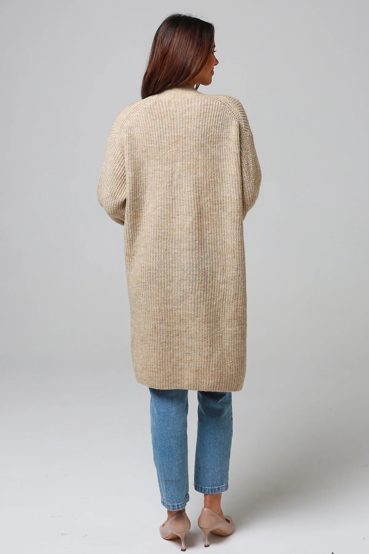 Woman wearing a beige longline knit cardigan with front pockets and jeans - neutral boho knitwear Australia.