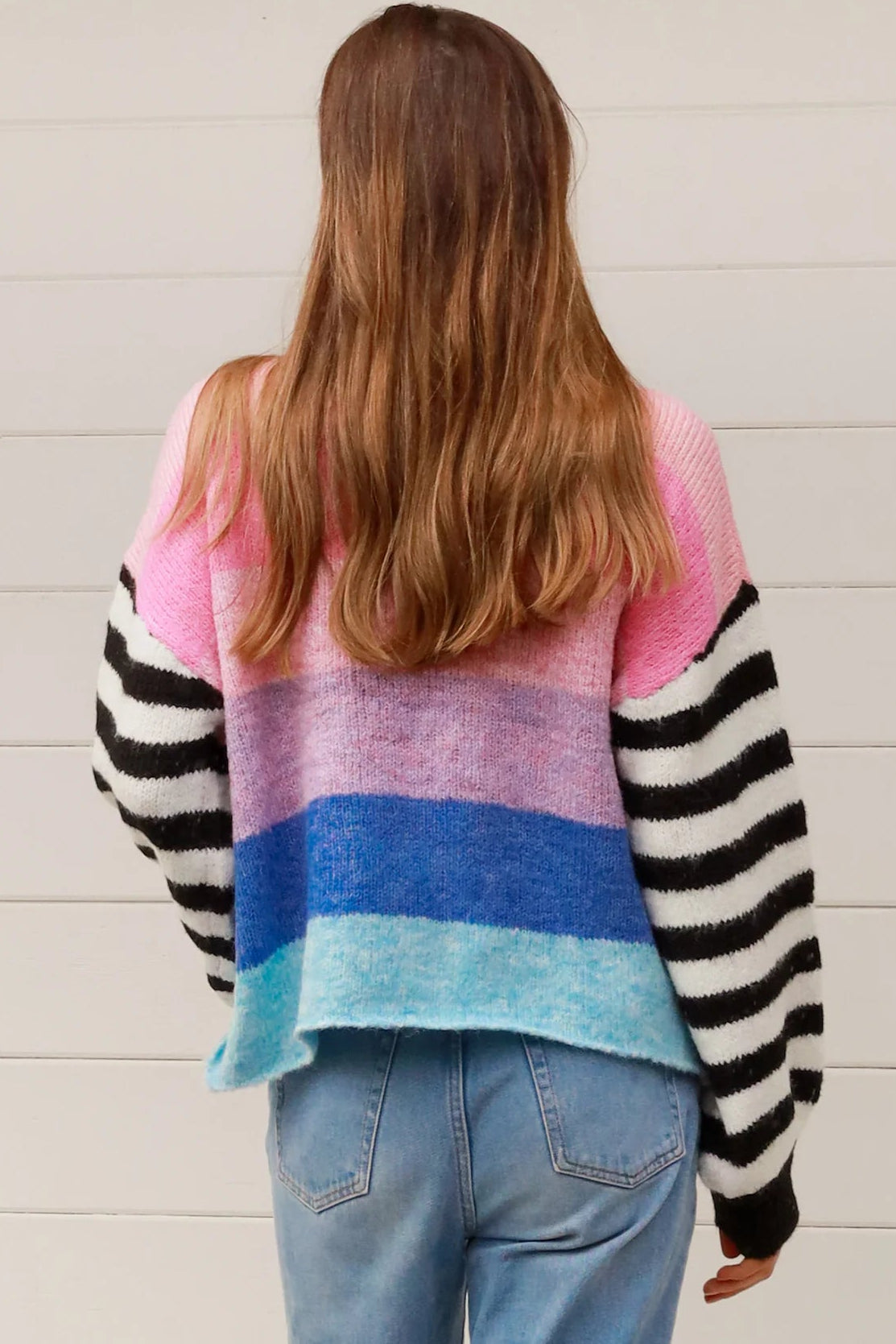 Woman wearing oversized pastel striped knit sweater with statement striped sleeves and relaxed winter boho styling in Australia