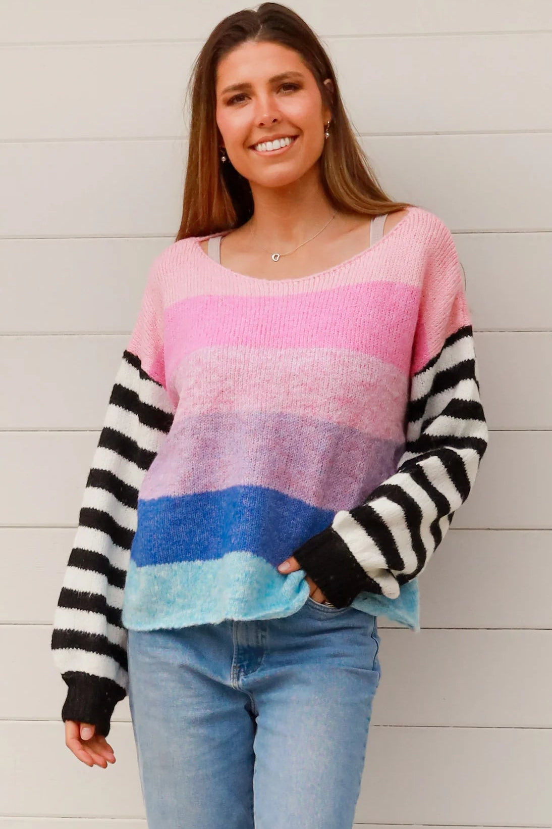 Woman wearing oversized pastel striped knit sweater with statement striped sleeves and relaxed winter boho styling in Australia