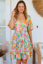 Woman in multicolour boho tiered mini dress with v-neckline, puff sleeves, shirred waist and oversized hemline - Australian bohemian style