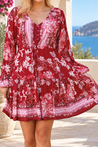 Claudette ruby red floral boho mini dress with blouson sleeves, drawstring waist, pockets and border print frill hem