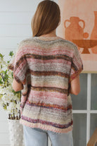 Woman wearing blush marled knit vest with textured finish layered over white top in natural indoor light