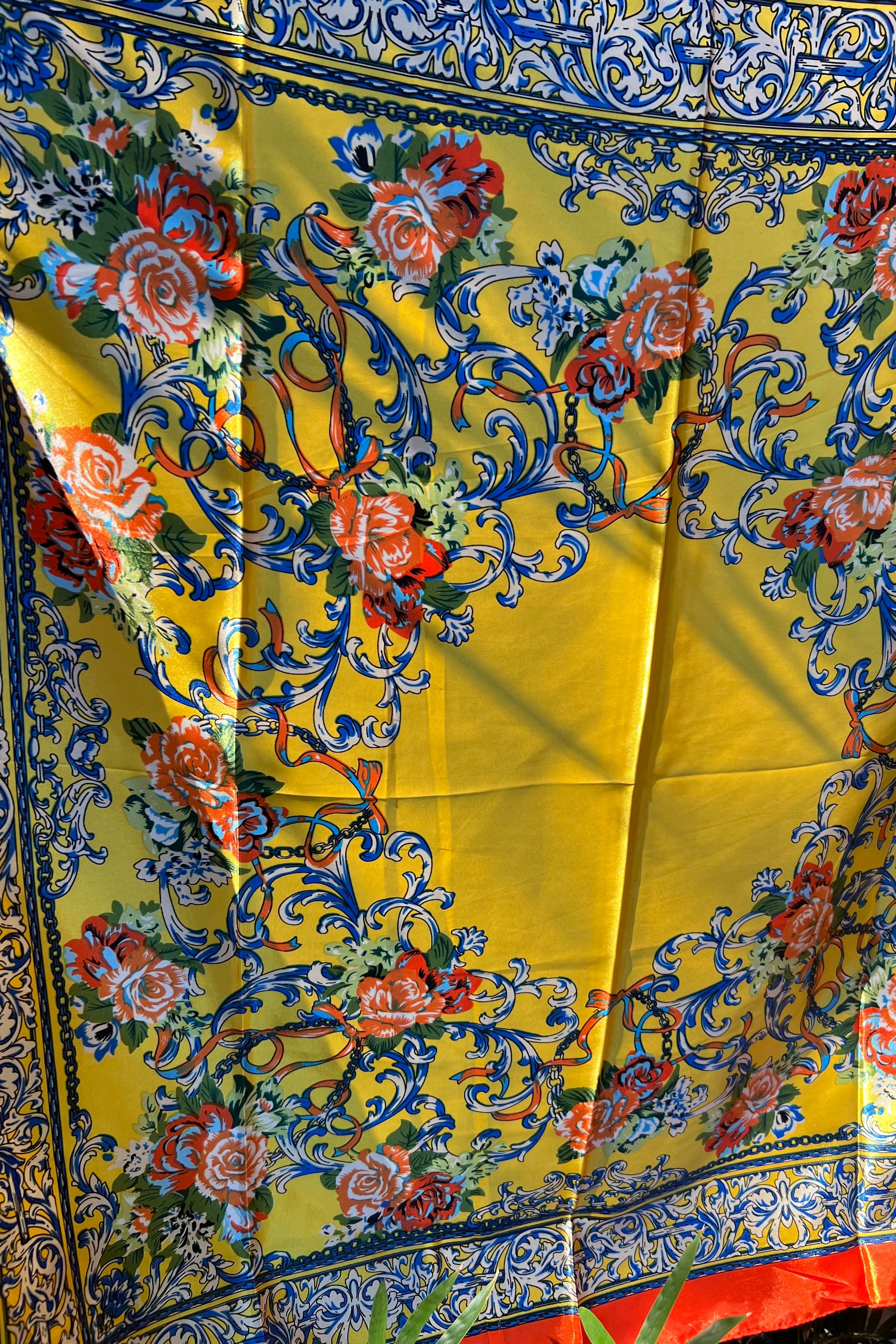 Yellow satin scarf with blue baroque scrolls and red floral print draped in sunlight - boho satin scarves Australia.