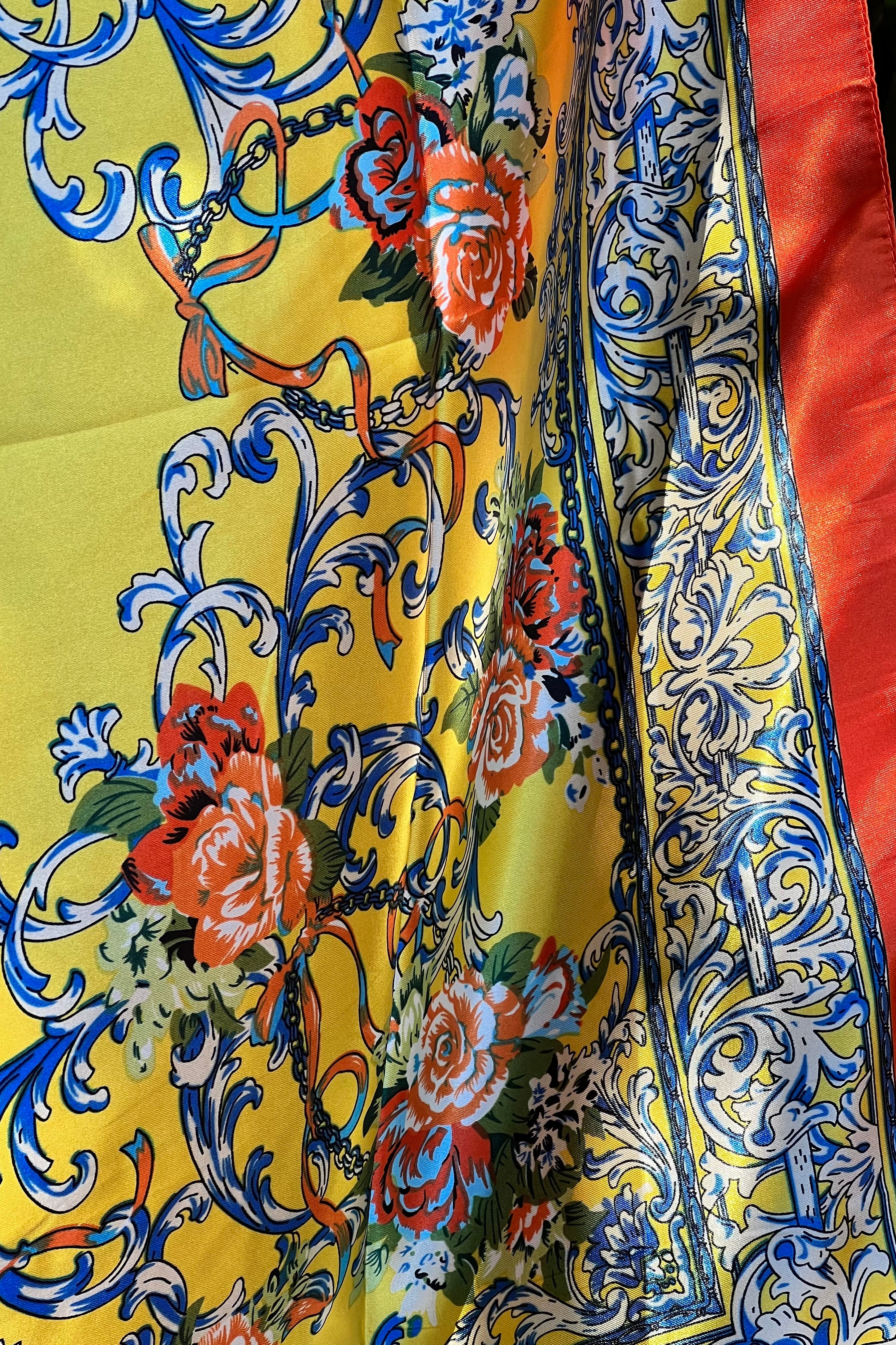 Yellow satin scarf with blue baroque scrolls and red floral print draped in sunlight - boho satin scarves Australia.