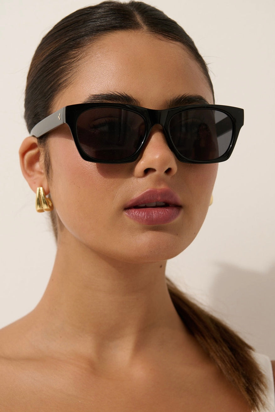 Woman wearing black square boho sunglasses with gold earrings and slick ponytail - vintage summer fashion Australia