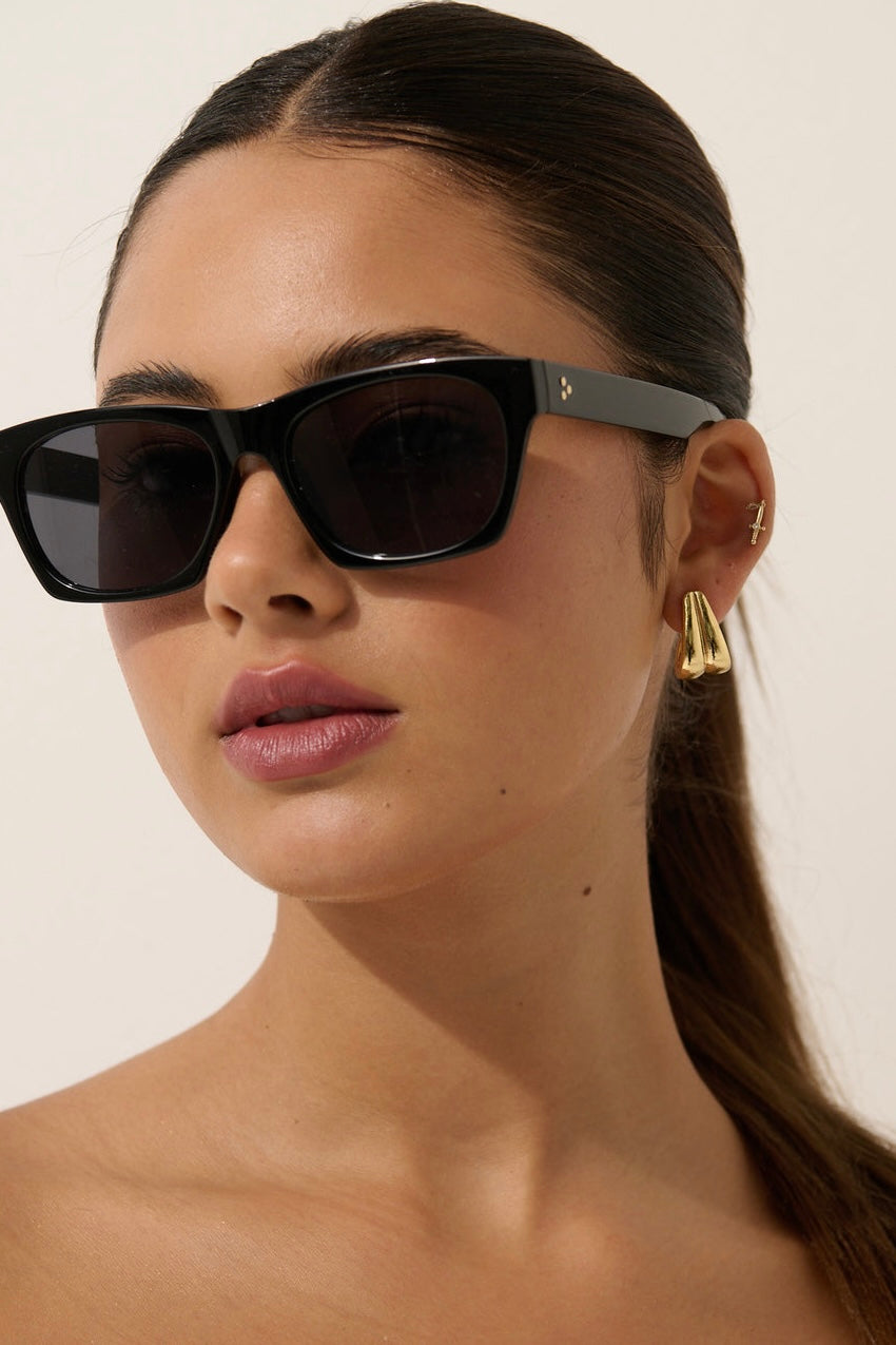 Woman wearing black square boho sunglasses with gold earrings and slick ponytail - vintage summer fashion Australia