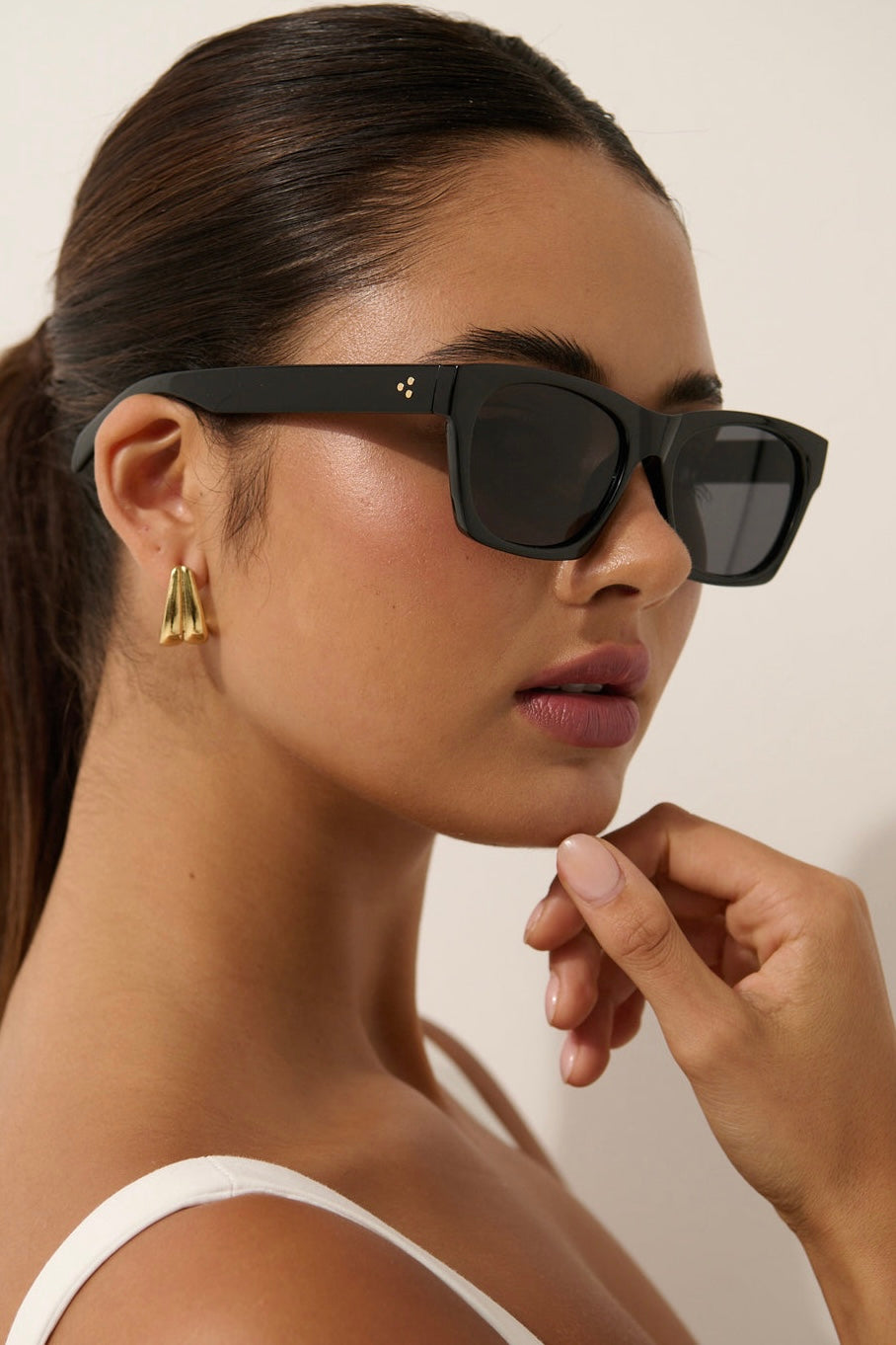 Woman wearing black square boho sunglasses with gold earrings and slick ponytail - vintage summer fashion Australia