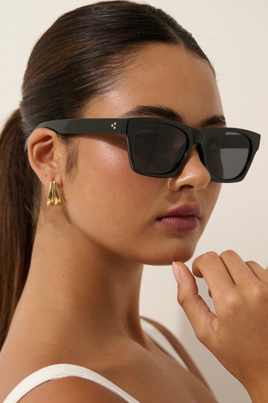 Woman wearing black square boho sunglasses with gold earrings and slick ponytail - vintage summer fashion Australia