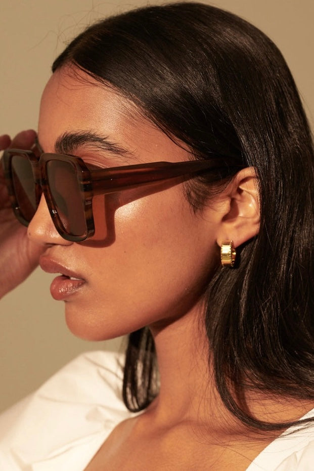 Woman in brown vintage square sunglasses with gold earrings and white shirt - tonal boho style Australia.