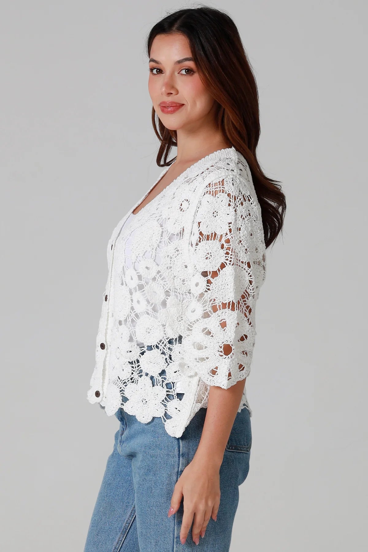 Woman wearing white floral crochet cardigan with scalloped hem - vintage-inspired boho knitwear Australia.