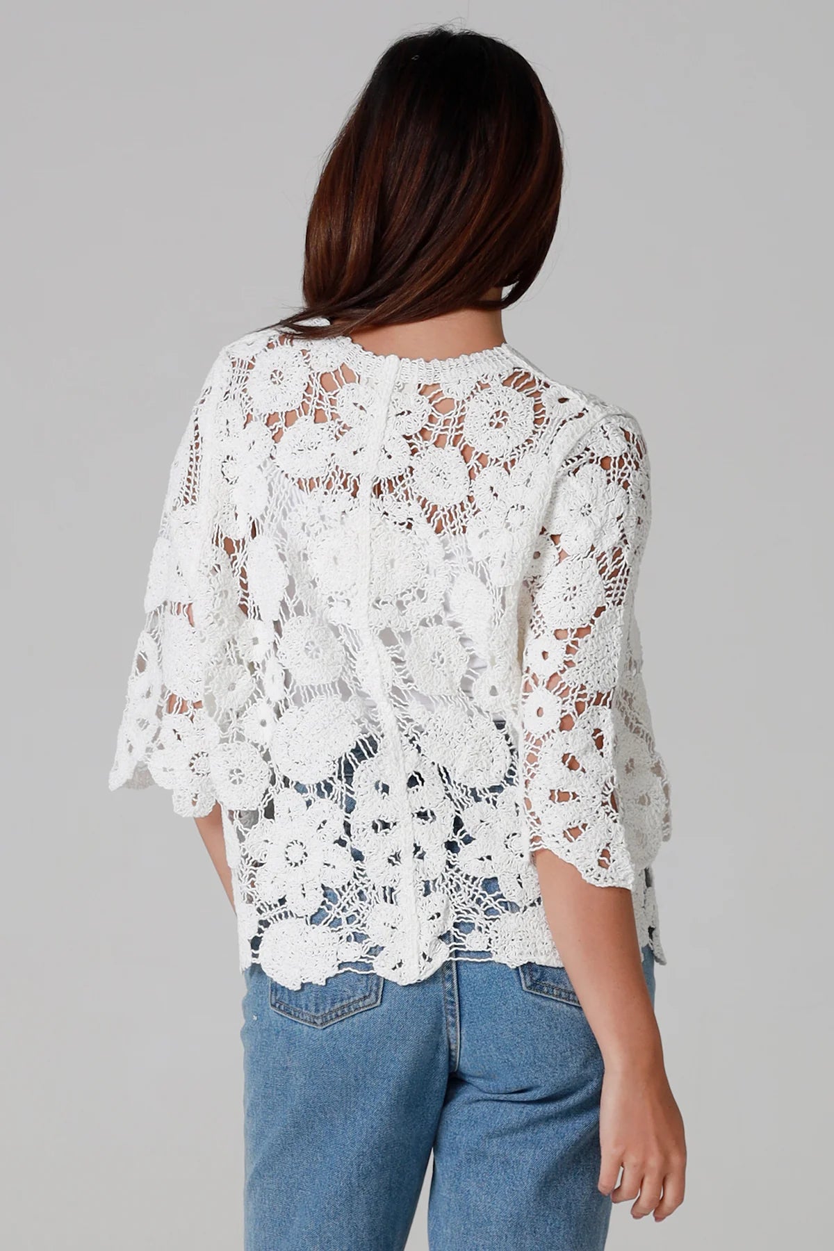 Woman wearing white floral crochet cardigan with scalloped hem - vintage-inspired boho knitwear Australia.