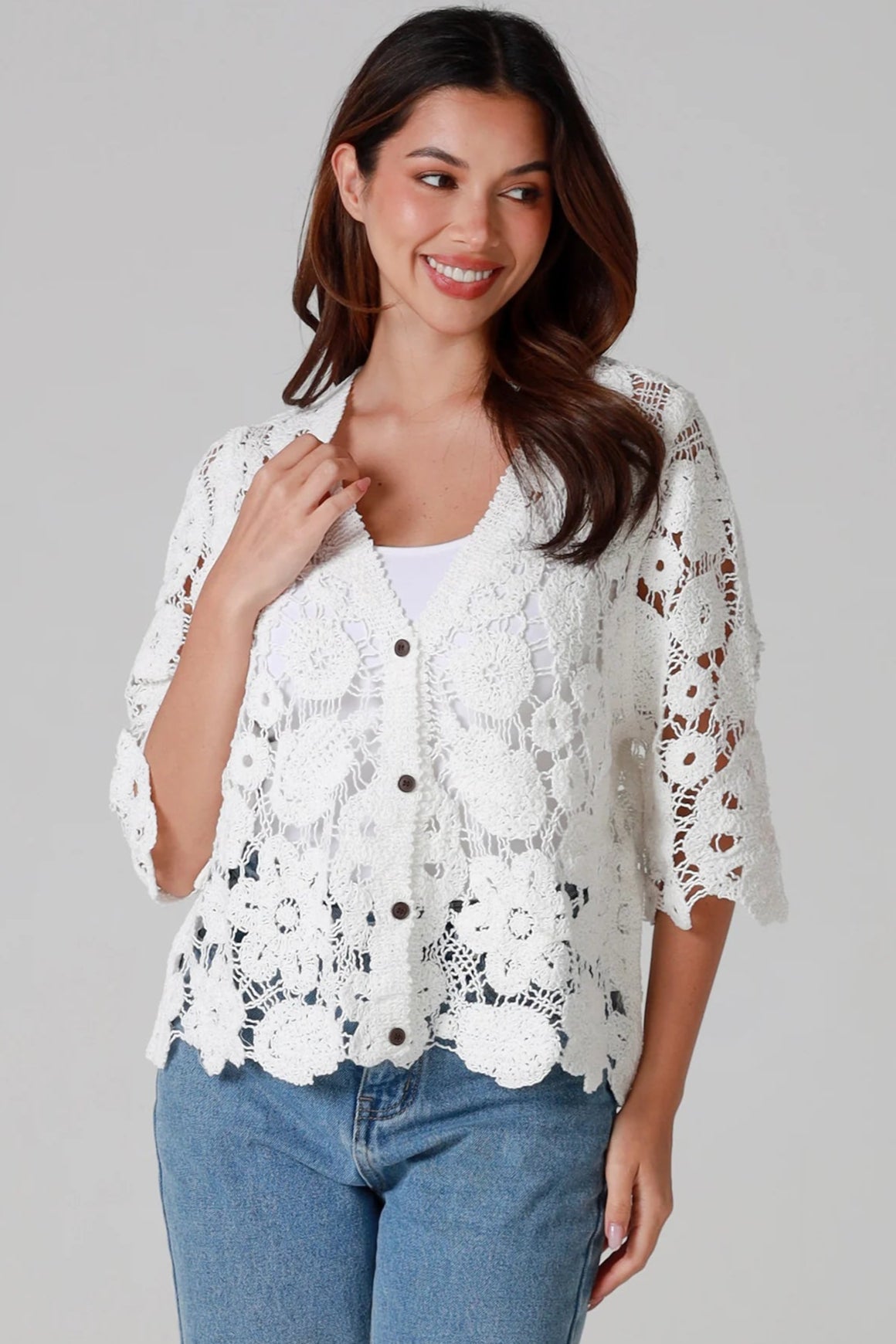 Woman wearing white floral crochet cardigan with scalloped hem - vintage-inspired boho knitwear Australia.