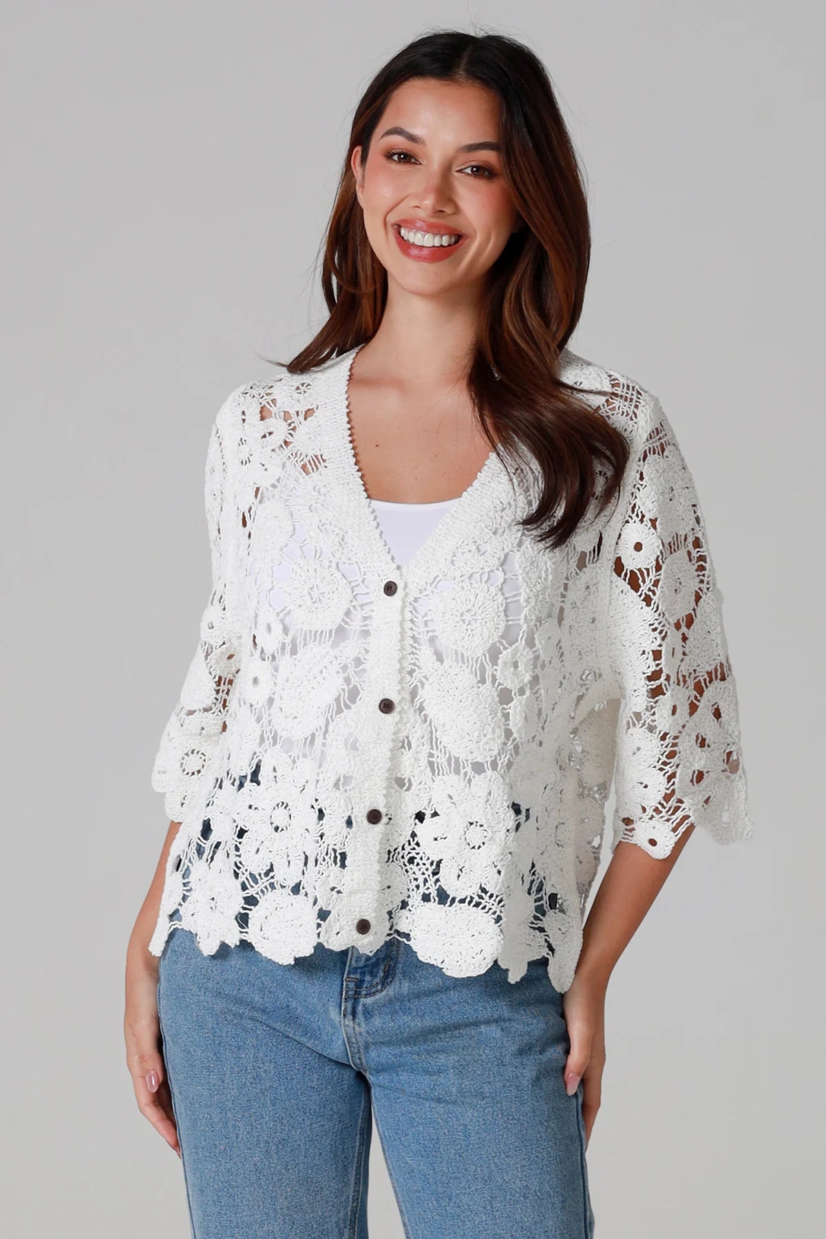 Woman wearing white floral crochet cardigan with scalloped hem - vintage-inspired boho knitwear Australia.