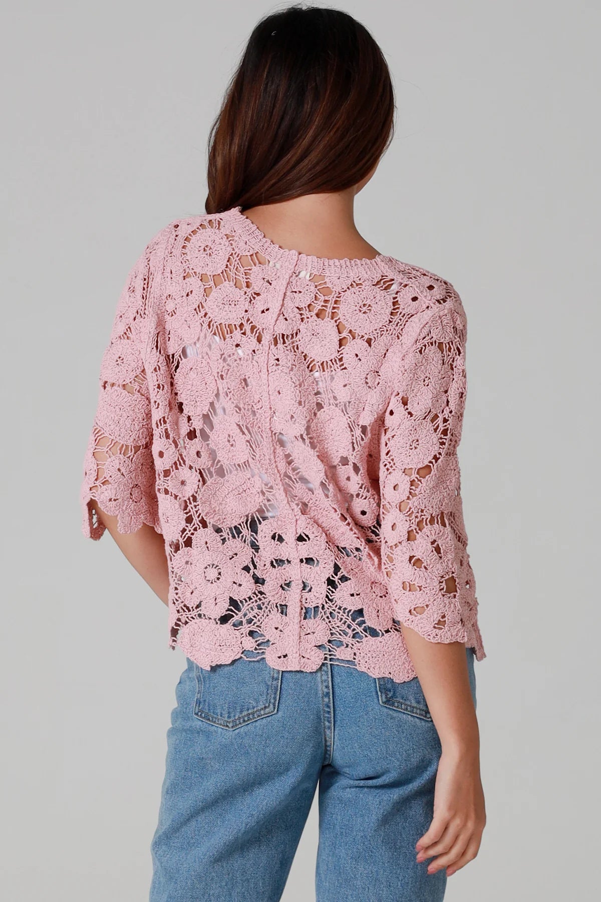 Woman in dusty rose pink floral crochet cardigan with scalloped hem - romantic boho knitwear Australia.