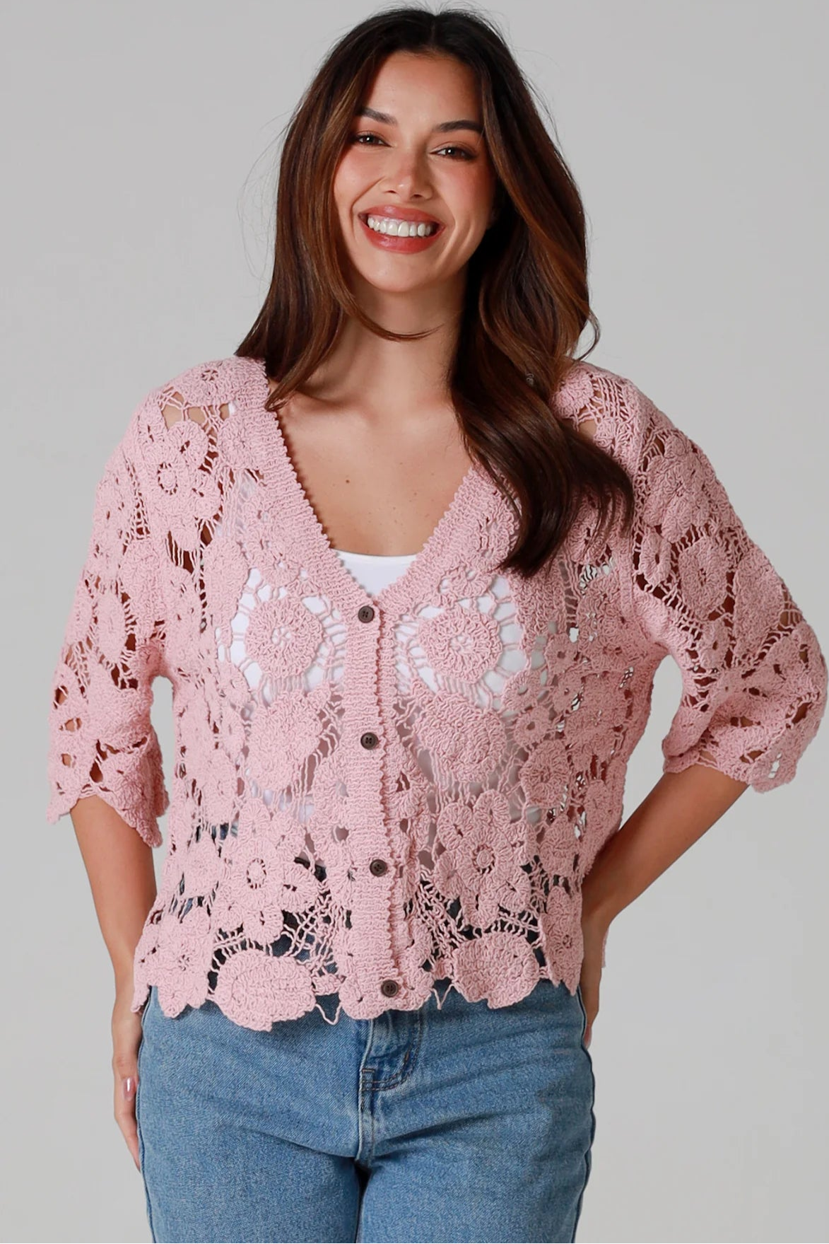 Woman in dusty rose pink floral crochet cardigan with scalloped hem - romantic boho knitwear Australia.