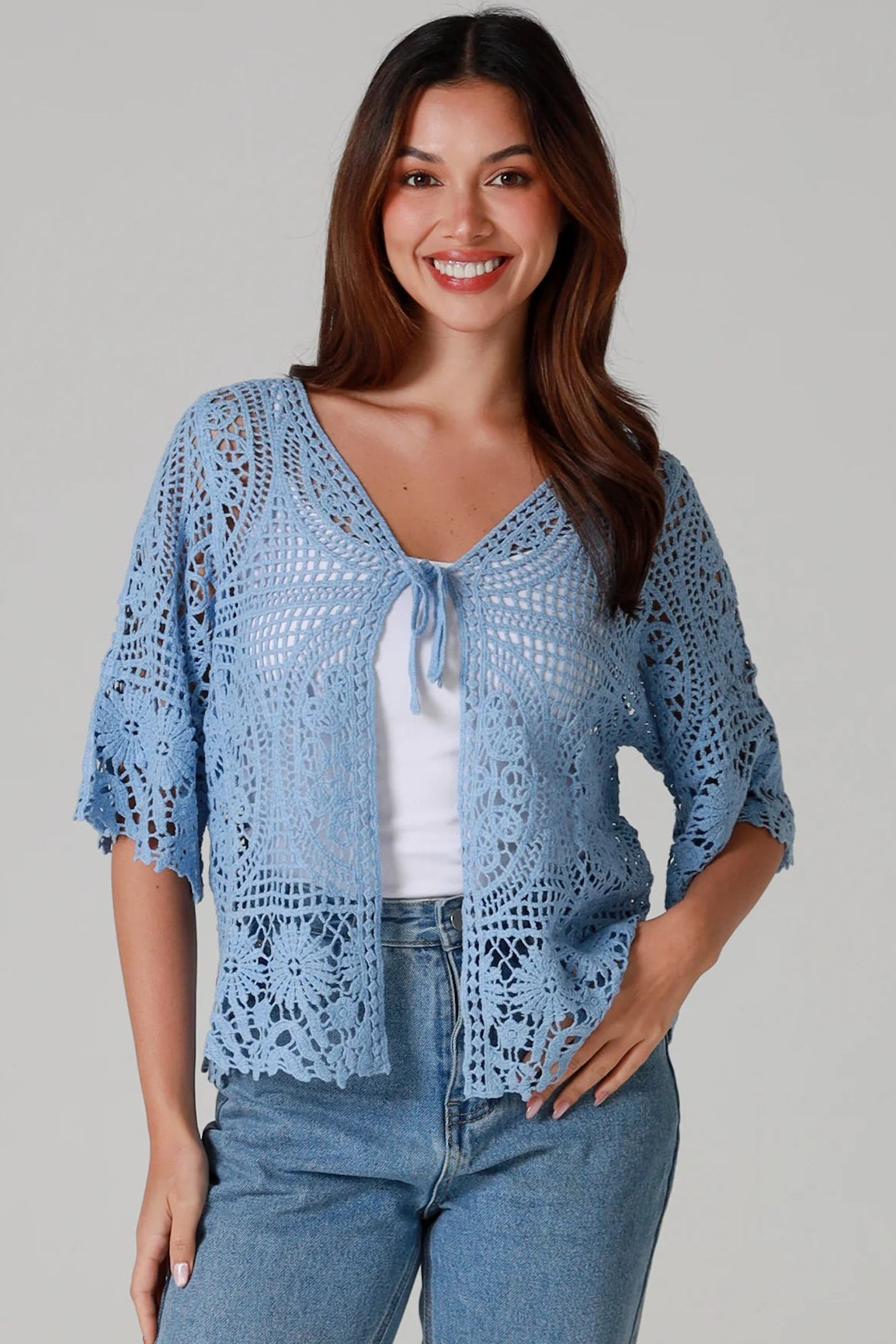 “Sky blue bohemian crochet cotton cardigan with scalloped sleeves and floral tie detail – boho knitwear Australia.”
