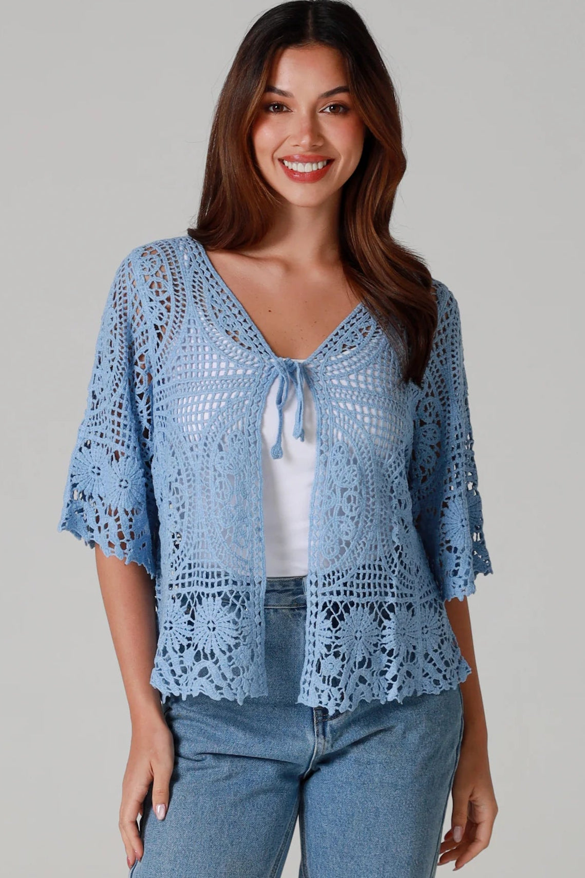 “Sky blue bohemian crochet cotton cardigan with scalloped sleeves and floral tie detail – boho knitwear Australia.”