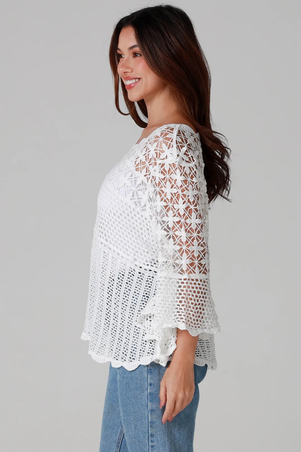 Woman wearing white cotton crochet top with scalloped hem and wide sleeves - Boho crochet blouse Australia.