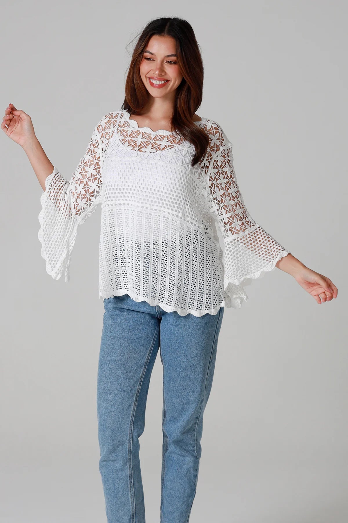 Woman wearing white cotton crochet top with scalloped hem and wide sleeves - Boho crochet blouse Australia.