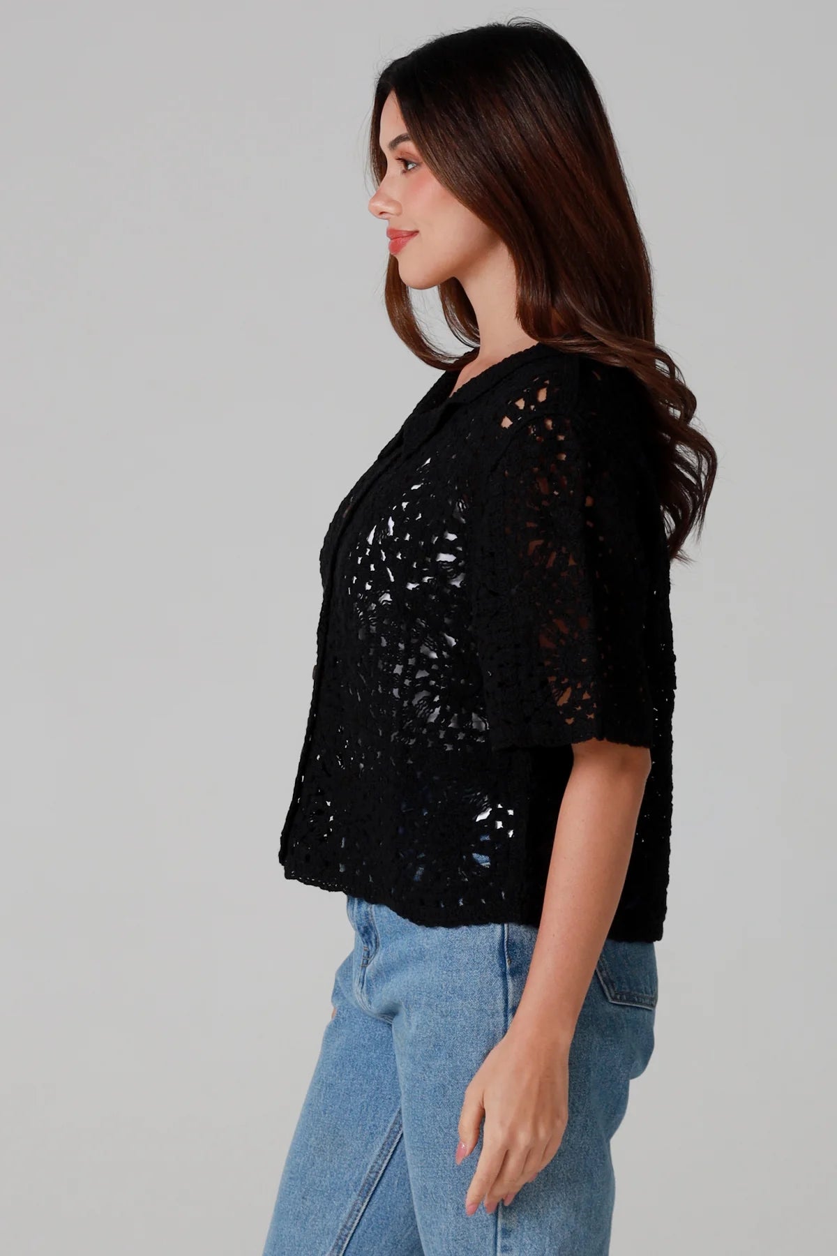 Woman wearing a black cotton crochet cardigan with collar and short sleeves styles with light blue jeans - boho crochet top Australia.