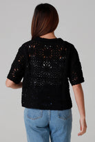 Woman wearing a black cotton crochet cardigan with collar and short sleeves styles with light blue jeans - boho crochet top Australia.
