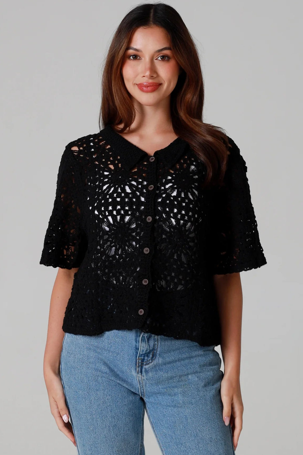 Woman wearing a black cotton crochet cardigan with collar and short sleeves styles with light blue jeans - boho crochet top Australia.