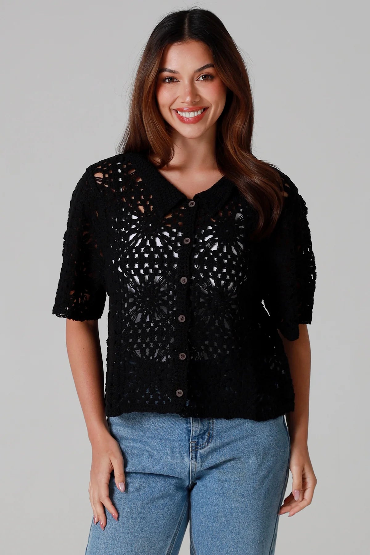 Woman wearing a black cotton crochet cardigan with collar and short sleeves styles with light blue jeans - boho crochet top Australia.
