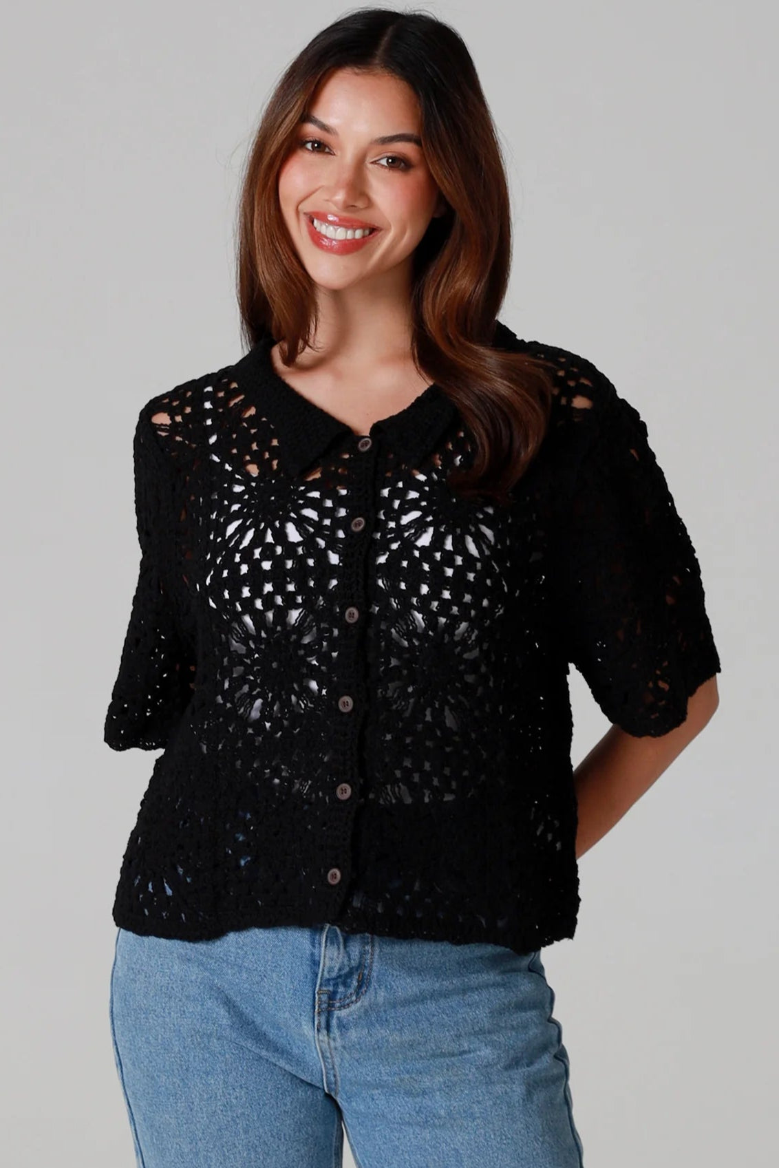 Woman wearing a black cotton crochet cardigan with collar and short sleeves styles with light blue jeans - boho crochet top Australia.